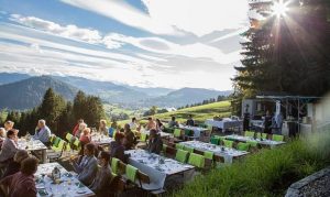 Menschen frühstücken auf der Sonnenterrasse mit Blick auf die Alpen