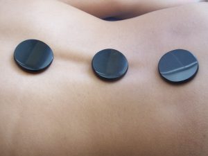 Kalte Steine bei einer Massage auf dem Rücken einer Frau